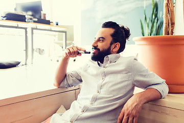 Image showing smiling man with beard and hair bun at office