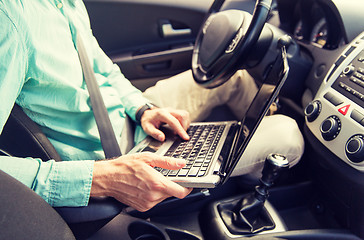 Image showing close up of young man with laptop driving car