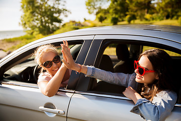 Image showing happy teenage girls or women in car at seaside