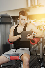 Image showing young man with tablet pc computer in gym