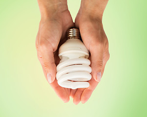 Image showing close up of hands holding energy saving lightbulb