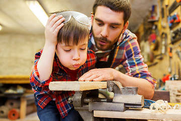 Image showing father and little son with wood plank at workshop