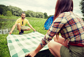 Image showing happy couple laying picnic blanket at campsite