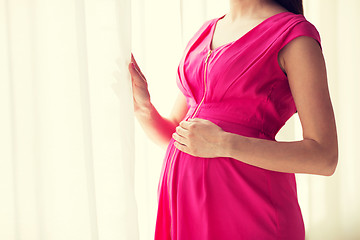 Image showing pregnant woman looking through window at home