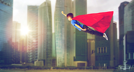 Image showing boy in superhero cape and mask flying over city