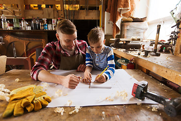 Image showing happy father and son with blueprint at workshop