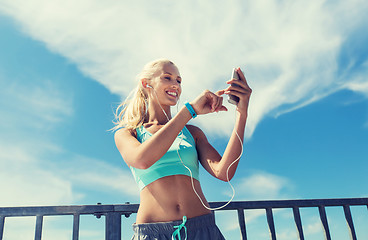 Image showing happy woman with smartphone and earphones outdoors