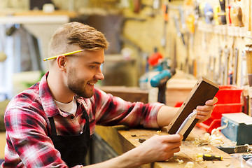 Image showing carpenter working with wood plank at workshop