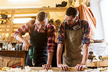 Image showing carpenters with drill drilling plank at workshop