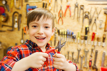 Image showing happy little boy with pliers at workshop