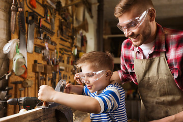 Image showing father and son with plane shaving wood at workshop