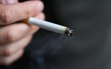 Image showing close up of male hand with smoking cigarette