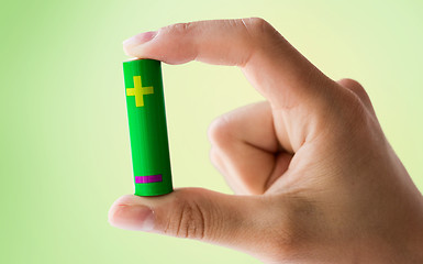 Image showing close up of hand holding green alkaline battery