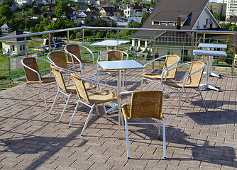 Image showing Wicker chairs with metal legs and racks are in an open cafe area