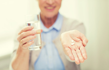 Image showing close up of senior woman with water and pills