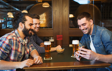 Image showing male friends with smartphone drinking beer at bar