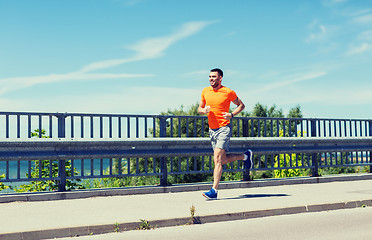 Image showing smiling young man running at summer seaside