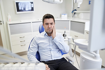 Image showing man having toothache and sitting on dental chair