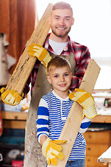 Image showing happy father and son with wood plank at workshop