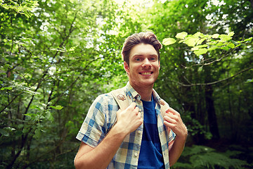 Image showing smiling young man with backpack hiking in woods