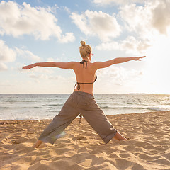 Image showing Woman practicing yoga on sea beach at sunset.