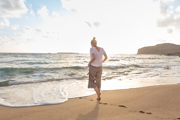 Image showing Woman walking on sand beach at golden hour