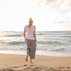 Image showing Woman walking on sand beach at golden hour