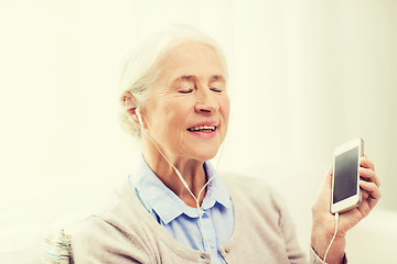 Image showing senior woman with smartphone and earphones at home