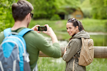 Image showing couple with backpacks taking picture by smartphone