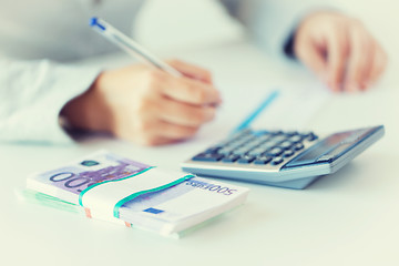 Image showing close up of hands counting money with calculator