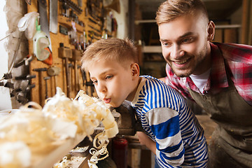 Image showing father and little son with wood plank at workshop