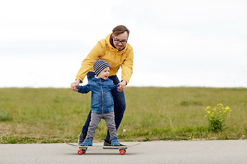 Image showing happy father and little son on skateboard