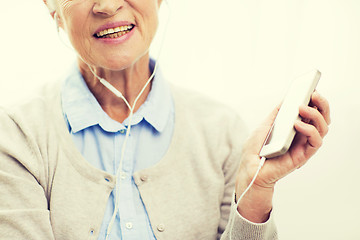 Image showing happy senior woman with smartphone and earphones