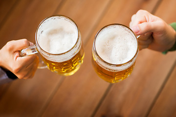 Image showing close up of hands with beer mugs at bar or pub