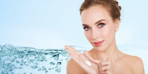 Image showing happy young woman with moisturizing cream on hand