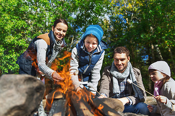 Image showing happy family roasting marshmallow over campfire