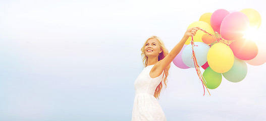 Image showing smiling woman with colorful balloons outside