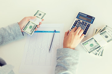 Image showing close up of hands counting money with calculator