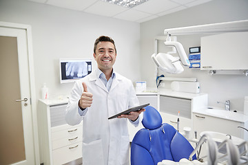 Image showing happy dentist showing thumbs up with tablet pc