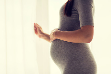 Image showing pregnant woman looking through window at home