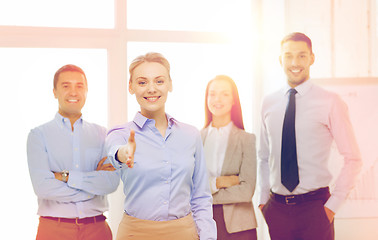 Image showing smiling businesswoman in office with team on back