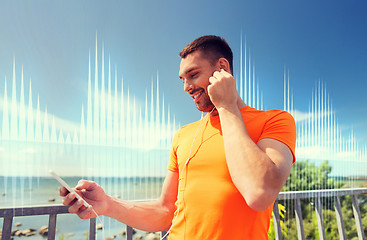 Image showing smiling young man with smartphone and earphones