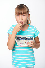 Image showing Little girl holding a box with bilberries and eating it