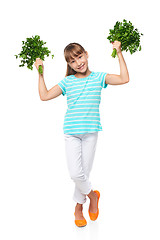 Image showing Smiling elementary school age girl showing fresh parsley