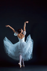 Image showing Portrait of the classical ballerina in white dress on black background