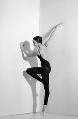 Image showing Ballerina in black outfit posing on pointe shoes, studio background.
