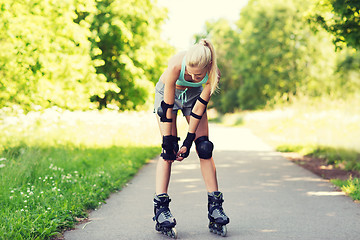 Image showing happy young woman in rollerskates riding outdoors