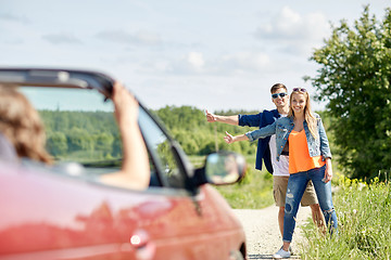 Image showing couple hitchhiking and stopping car on countryside