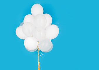 Image showing close up of white helium balloons over blue