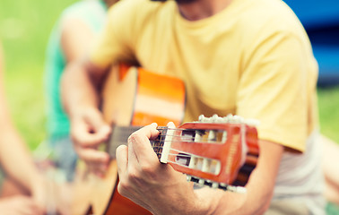 Image showing close up of man playing guitar at camping